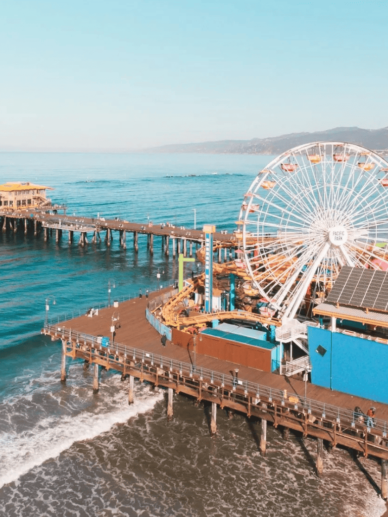 Bright Ferris wheel and ocean pier at Pacific Park amusement park, Santa Monica California.
