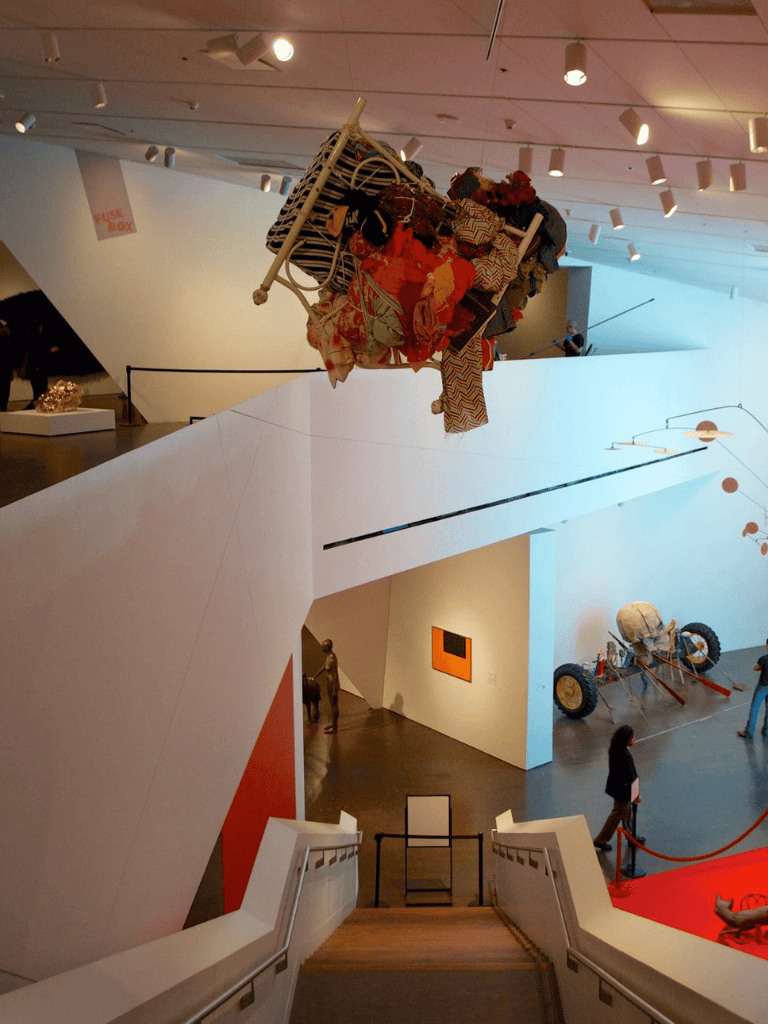 Cluttered art installation with furniture and textiles hanging from the ceiling at QuestForDirections museum.