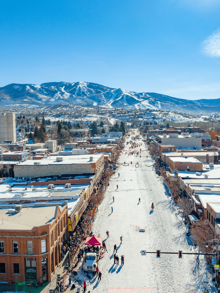 Skier and winter sports enthusiasts in downtown winter cityscape with snowy mountains, holiday market and festive atmosphere.