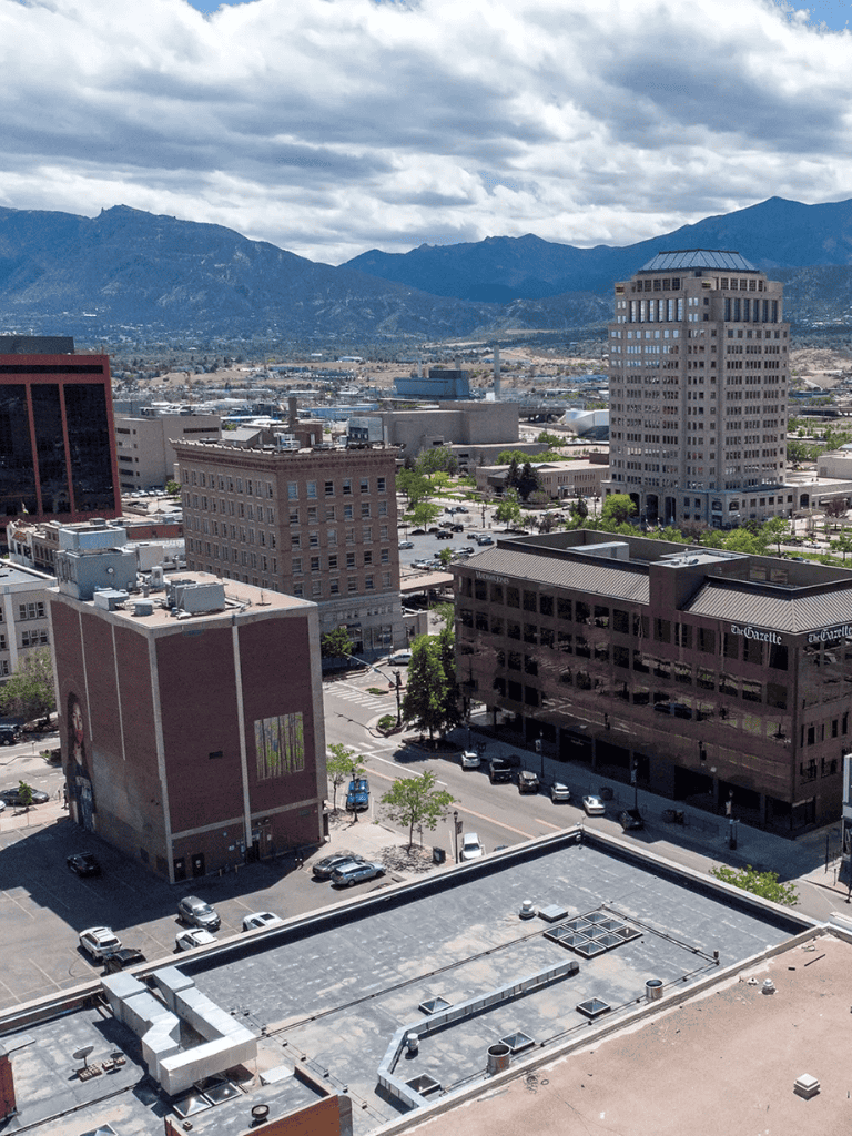 Aerial view of downtown with mountains in the background, showcasing cityscape and office buildings.