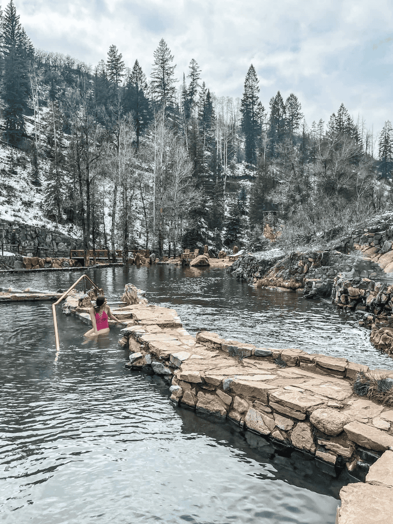 Relaxing hot springs surrounded by snowy mountains and forest in summertime.