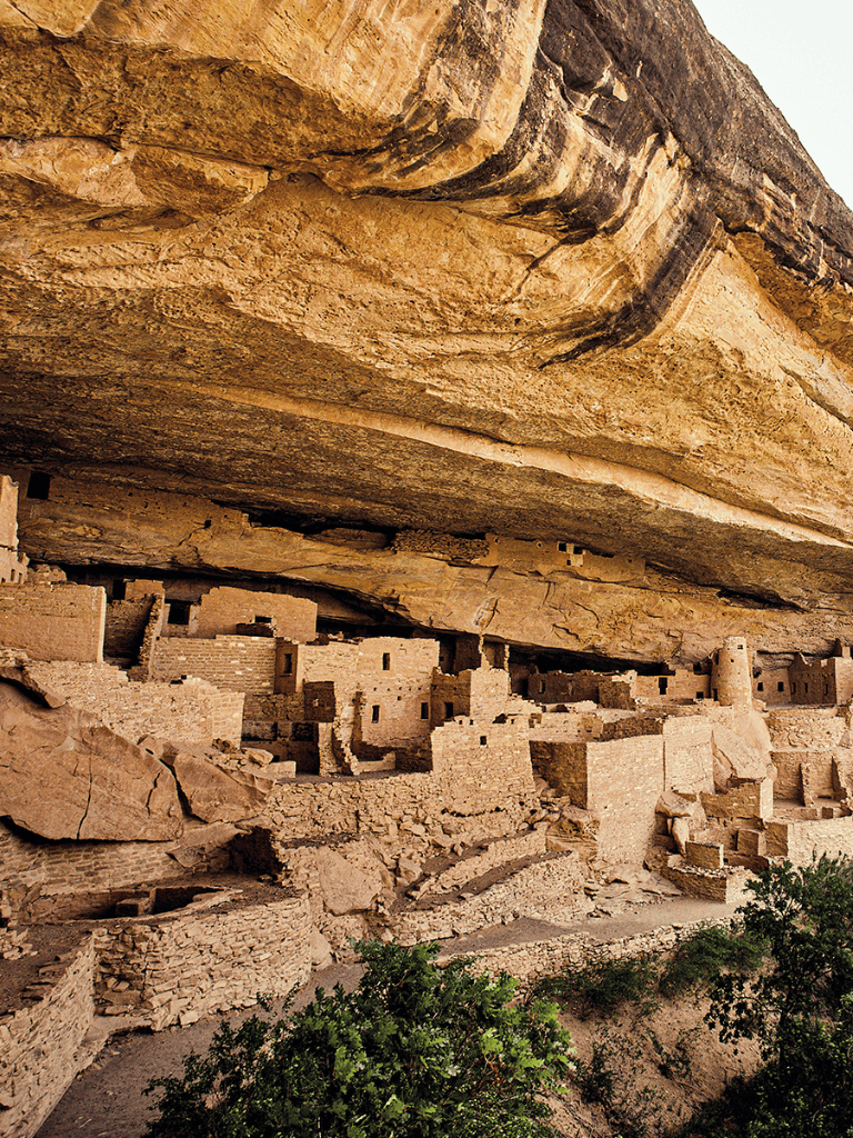 Ancient cliff dwellings built into a massive rock formation, showcasing native American archaeological sites.