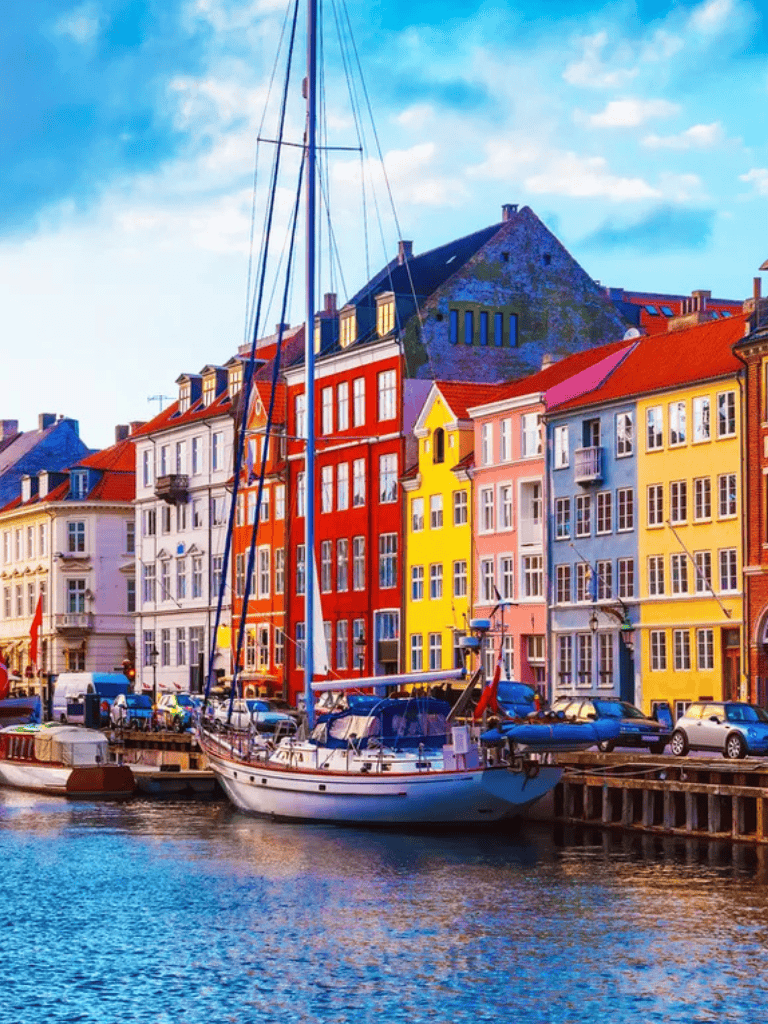 Colorful Nordic waterfront with boats and vibrant buildings in Copenhagen, Denmark.