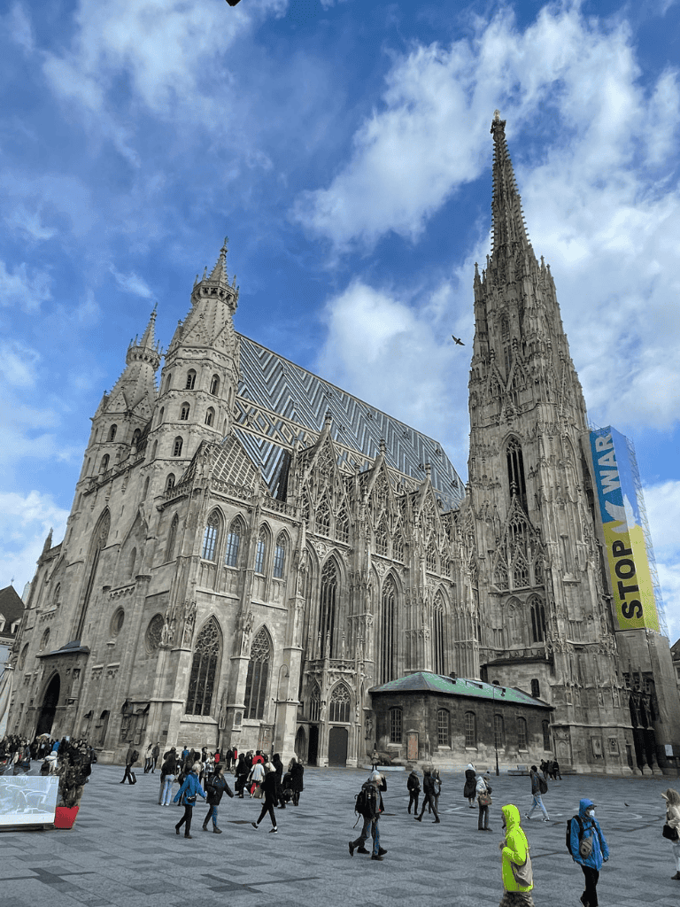Intricate Gothic cathedral with towering spires and detailed stonework under a blue sky.