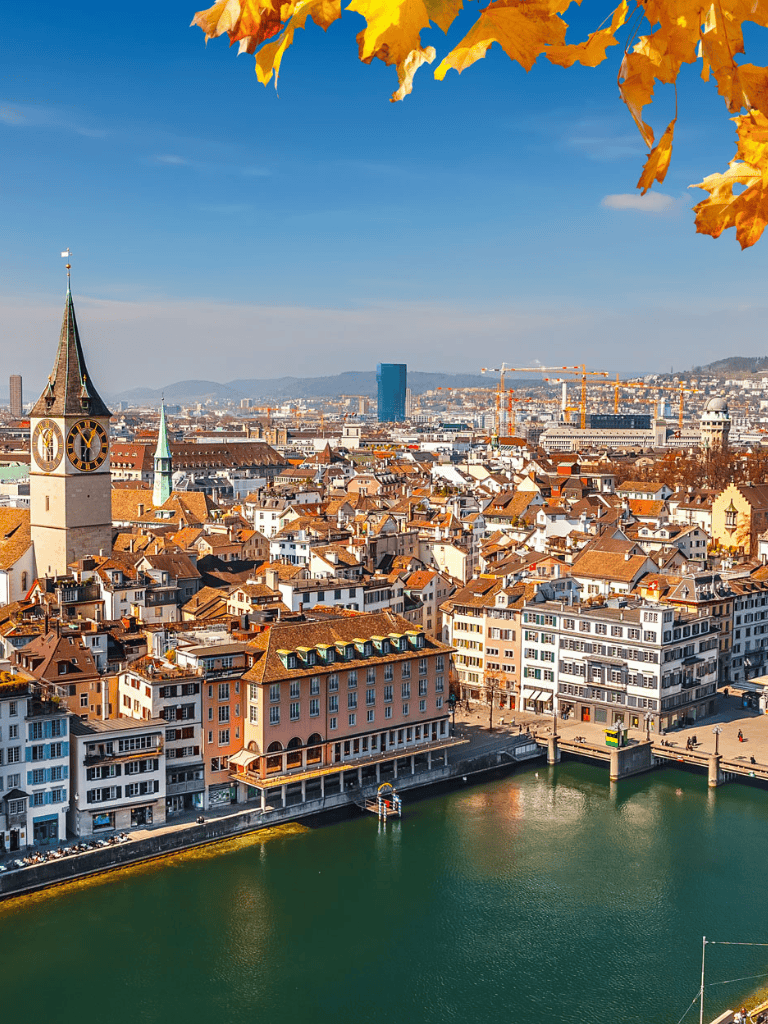 Panoramic view of Zurich cityscape with historic church and modern buildings, a vibrant travel destination guide.