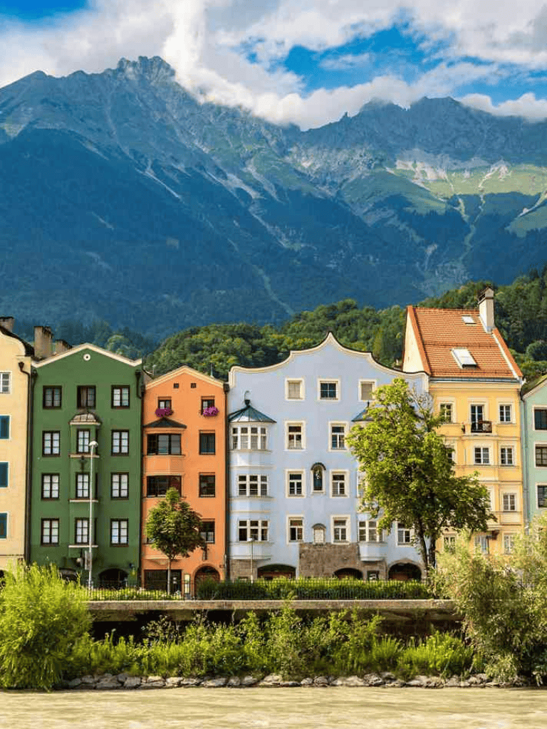 Colorful European houses with mountain backdrop in Innsbruck, Austria.