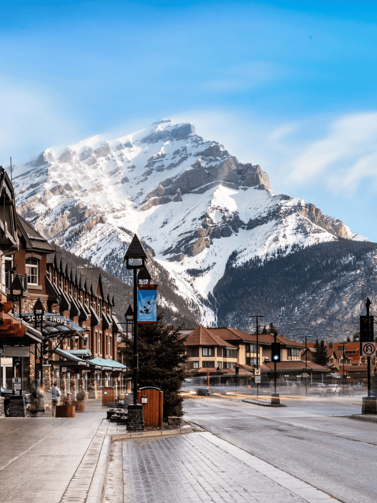 Snow-capped mountains behind charming town with shops and restaurants, scenic mountain village in winter.