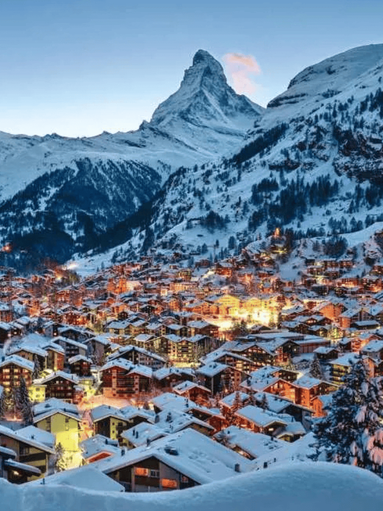 Snowy mountain village below Matterhorn at dusk, popular ski destination in the Swiss Alps.