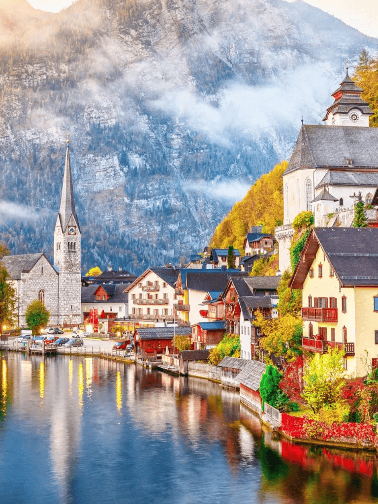 Charming European village with mountains, colorful houses, church, and river scenery.