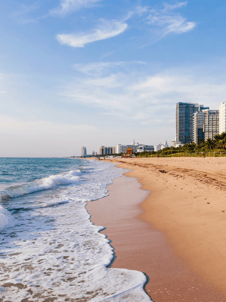 Sunny beach with high-rise buildings and clear blue sky, perfect for travel and vacation planning.
