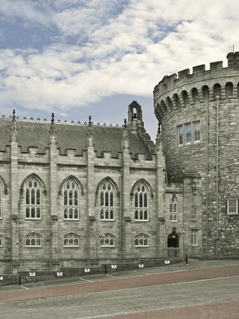 Victorian castle with grey stone walls and pointed windows, under a partly cloudy sky.