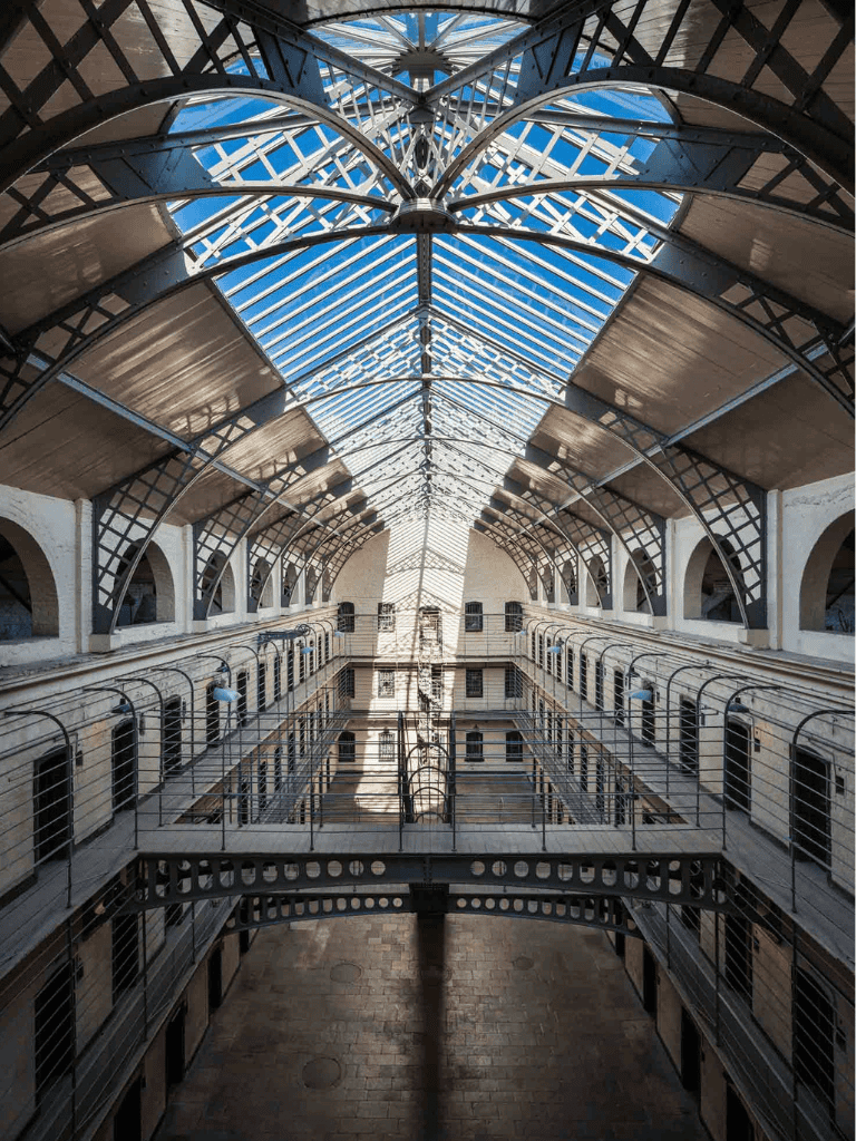 Aerial view of historic multi-story building with glass roof and iron balconies, showcasing architectural elegance.