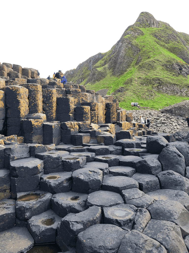 Ancient basalt columns at Giant's Causeway, Ireland, with hikers exploring the geological site.