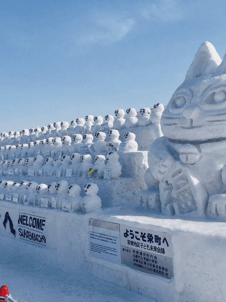 Colorful snow sculptures of animals, including polar bears and a large dragon face, at a winter snow sculpture festival.