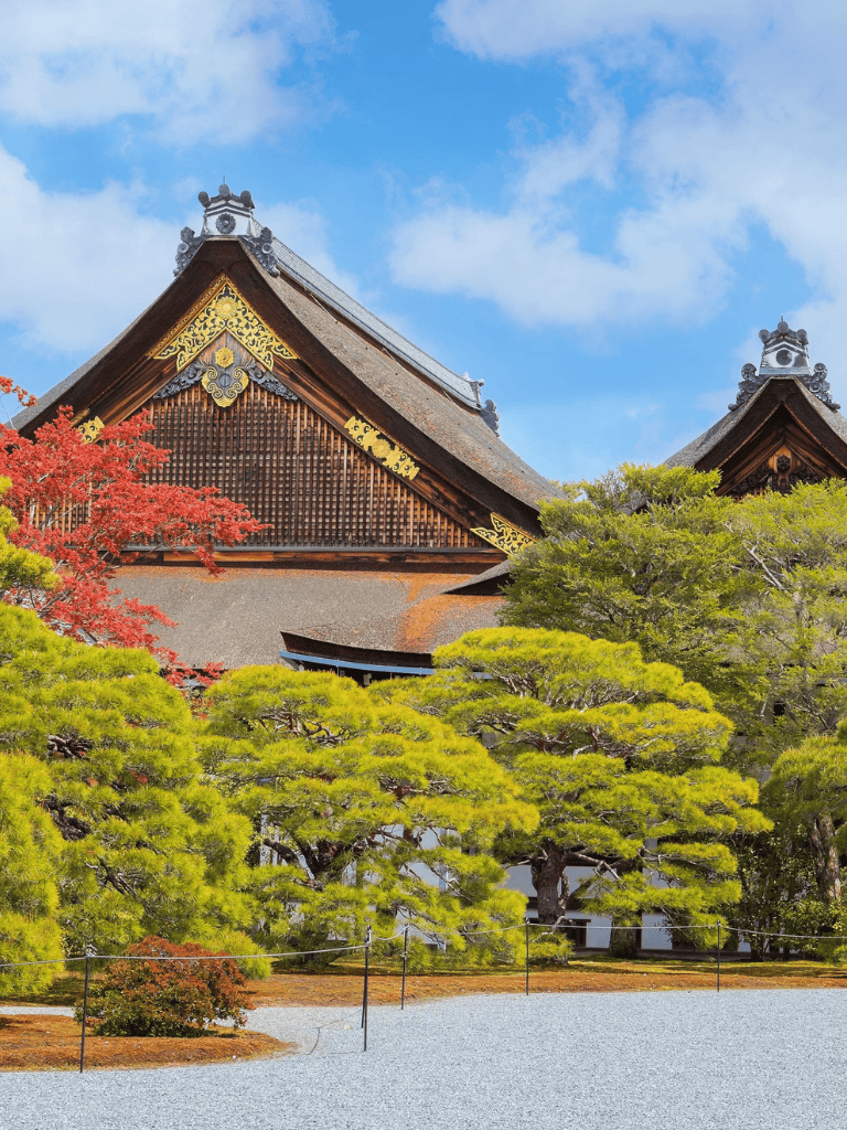Traditional Japanese temple surrounded by lush greenery and vibrant autumn leaves.