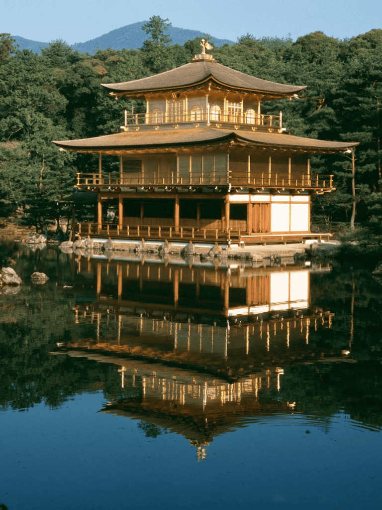 Tranquil traditional Japanese temple reflected in a serene pond surrounded by lush greenery.