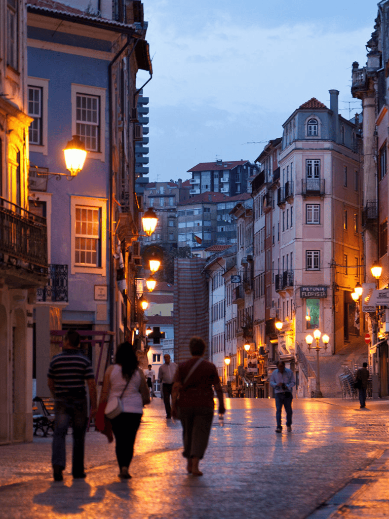 Colorful European street at dusk with historic buildings and street lamps.