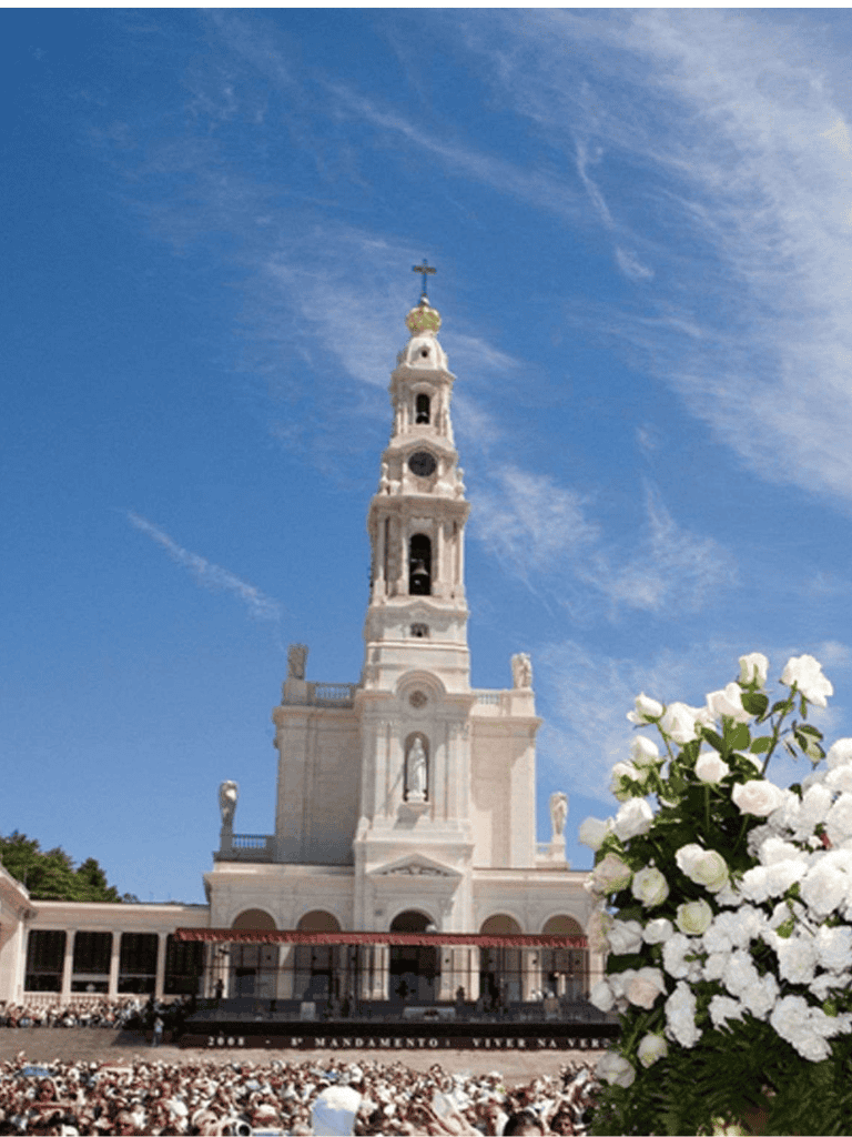 Iconic white church tower with cross, blue sky, and white flowers in foreground, offering direction to spiritual travelers.
