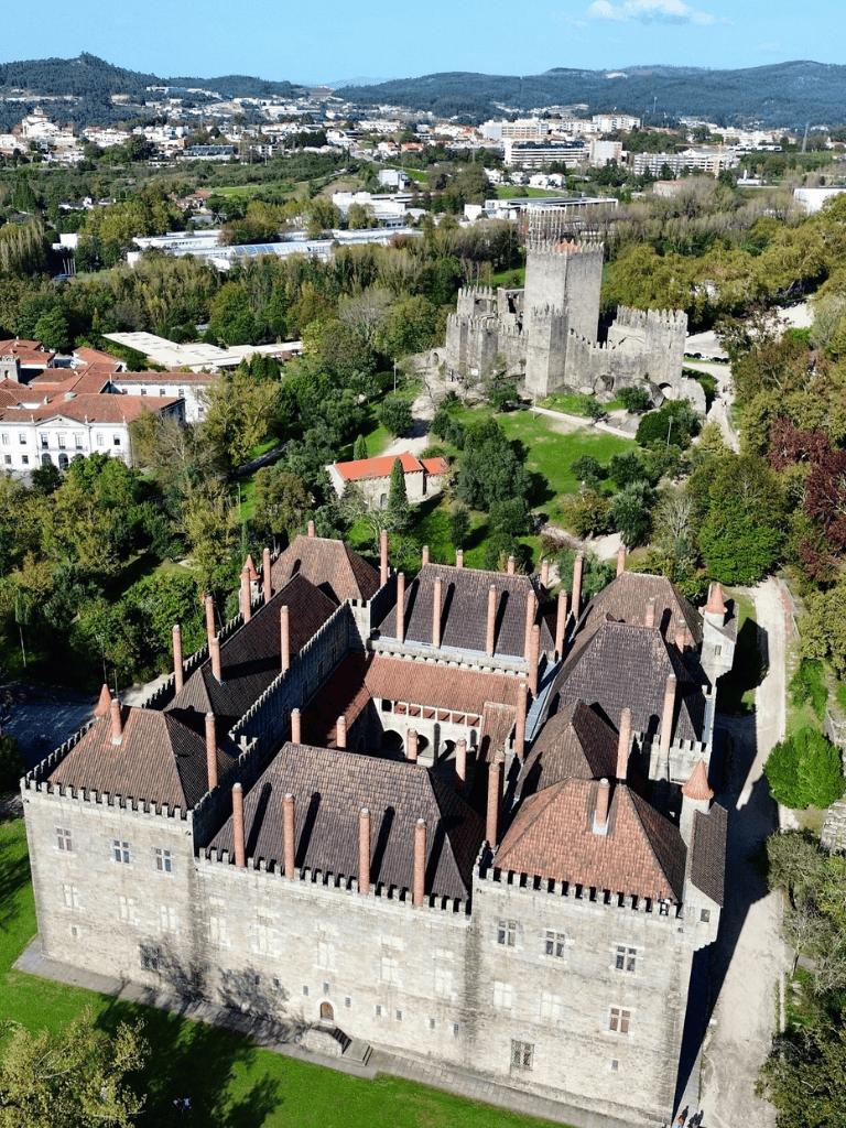 Medieval stone castle with battlements, surrounded by lush greenery in an urban setting.