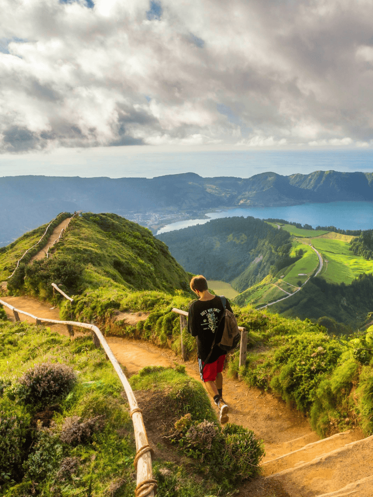 Hiking trail on scenic lush green mountain with traveler enjoying nature views.