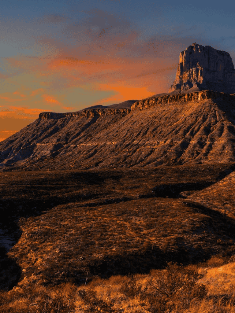 Sunset over rugged canyon landscape with rock formations and dramatic sky, scenic travel destination.