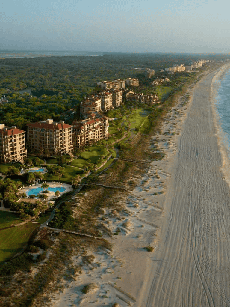 Luxurious beachfront condos and resort lifestyle on the sandy coast with lush greenery.