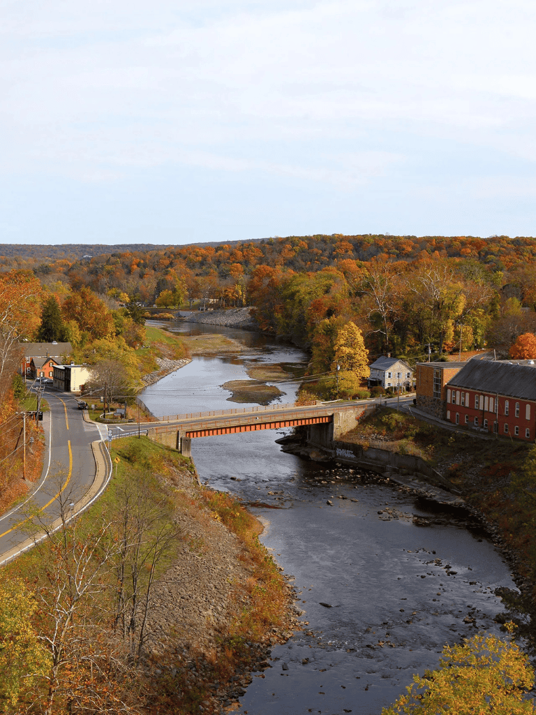 Scenic river view with colorful autumn trees and small town, perfect for travel and outdoor exploration.