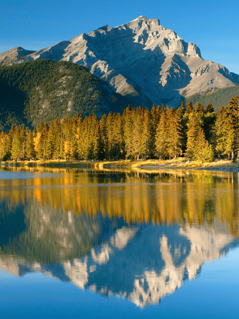 Serene mountain lake with lush forest and towering peaks, perfect for outdoor adventure and nature exploration.