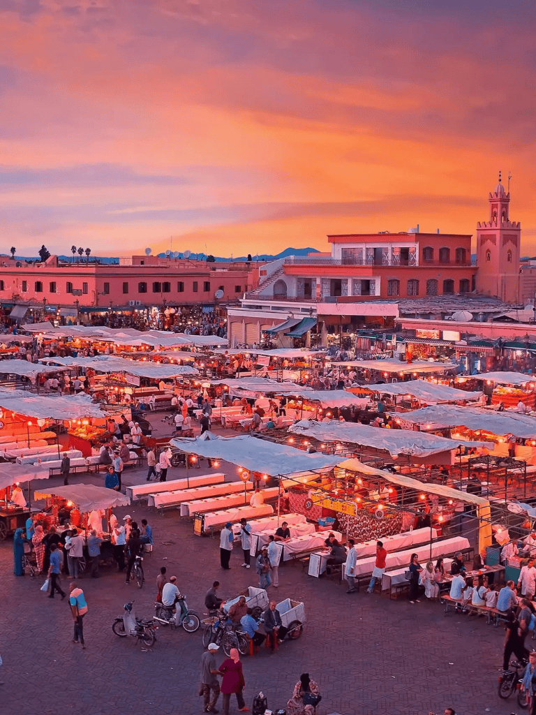 Vibrant Moroccan market at sunset with colorful stalls and lively crowd, showcasing local culture and cuisine.