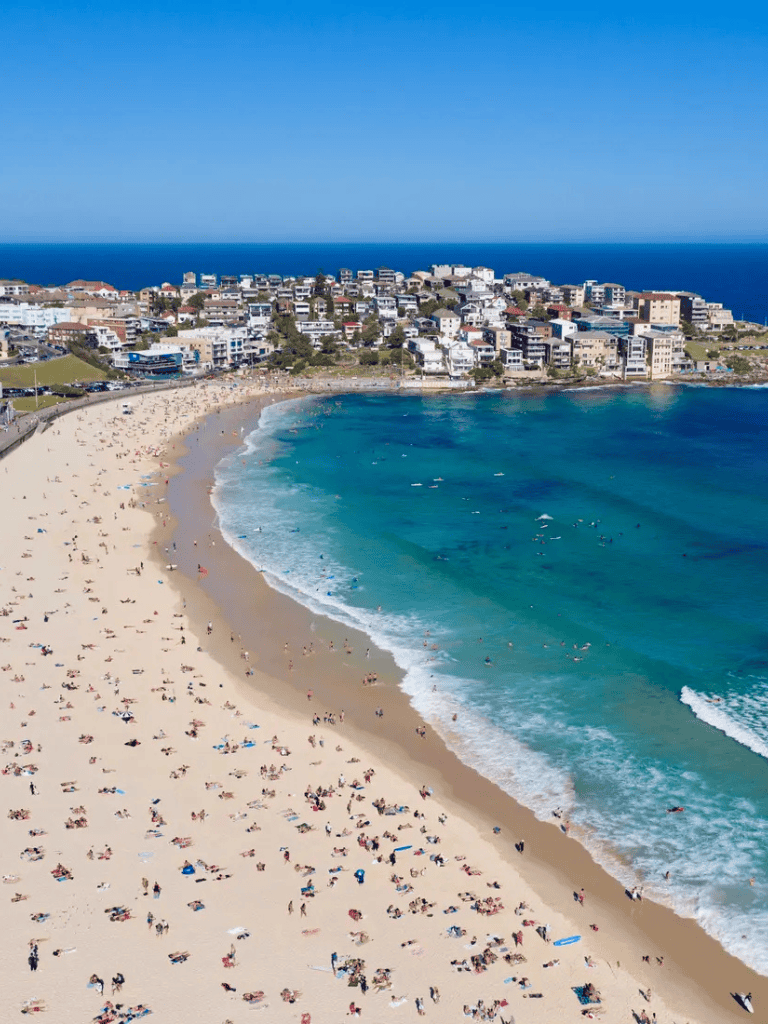Beachside cityscape with ocean view, coastal residential buildings, and crowded sandy beach.