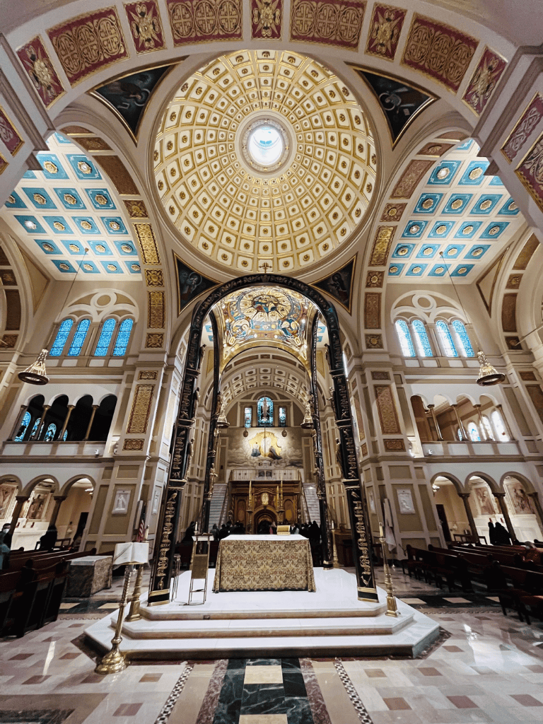 Ornate church interior with grand altar and detailed gold accents, sacred space with stained glass windows.
