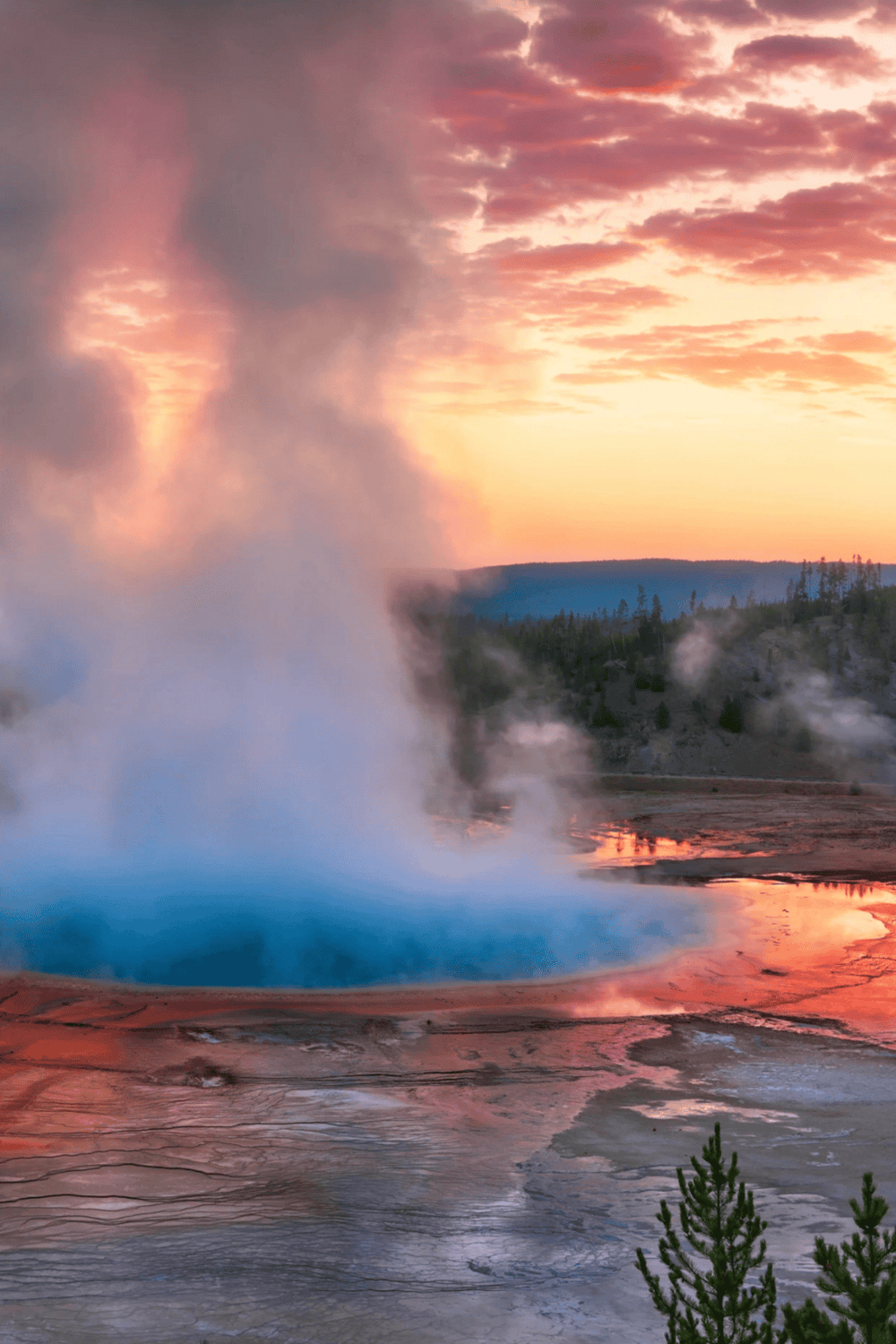 Vibrant geothermal hot spring at sunset with colorful sky and steam rising, showcasing natural attractions and scenic views.