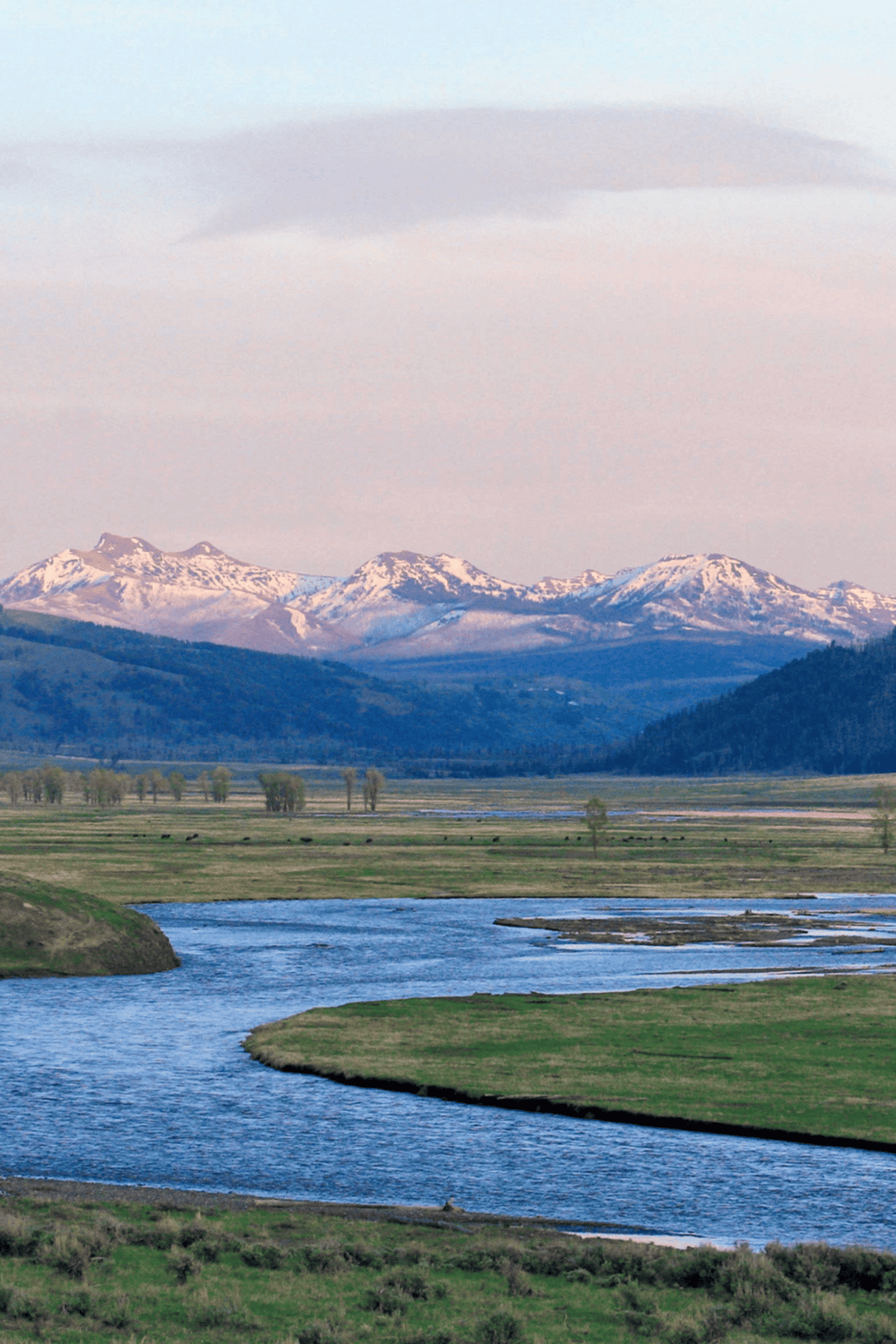 Serene mountain landscape with snow-capped peaks and flowing river, perfect for travel and outdoor adventure keywords.