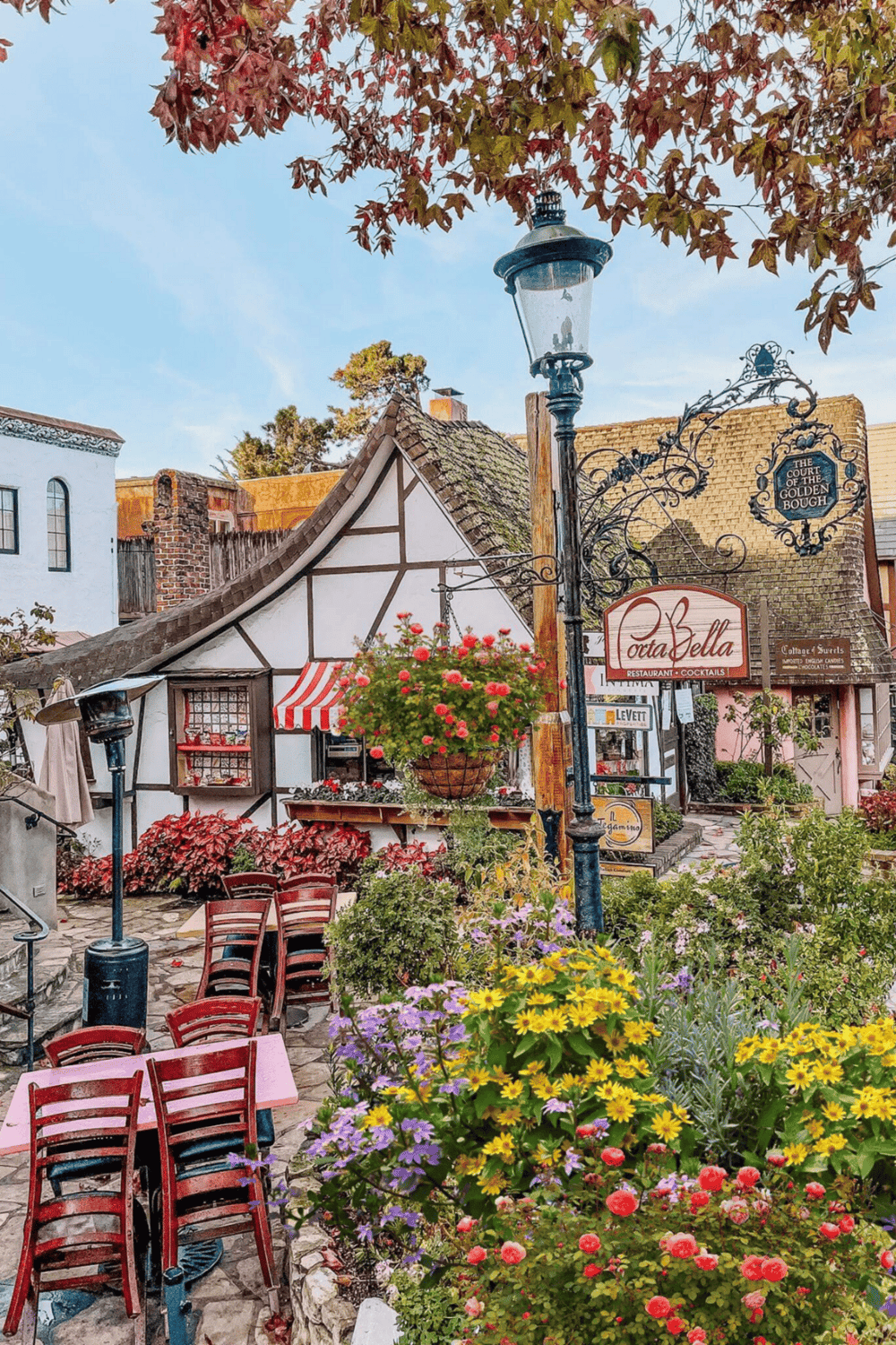 Charming European-style street scene with colorful flowers, outdoor seating, and quaint buildings.