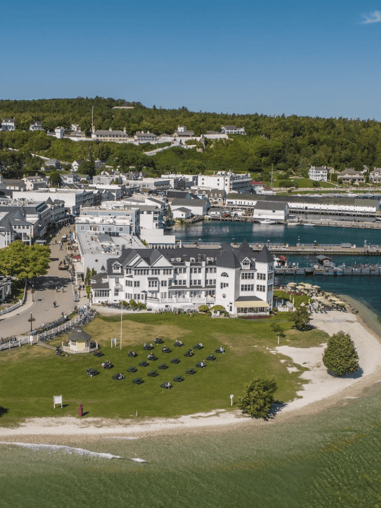 Harbor town with waterfront buildings and green park area, scenic coastal view, popular vacation destination.