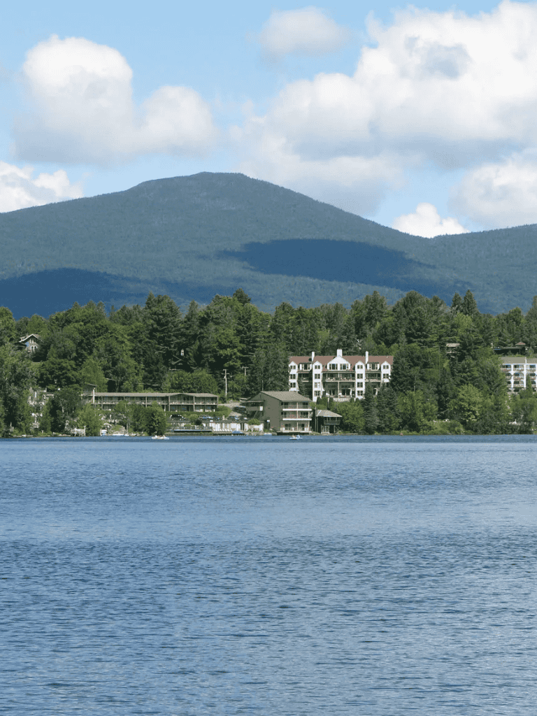 Serene lake with mountains, waterfront homes, and lush green trees, ideal for travel and outdoor activities.