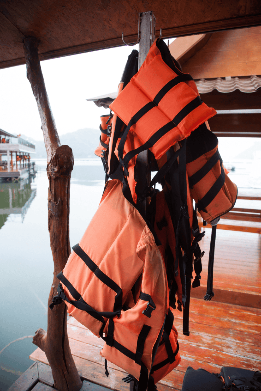 1. Bright orange life vest hanging on a wooden post by the water, ready for water safety.