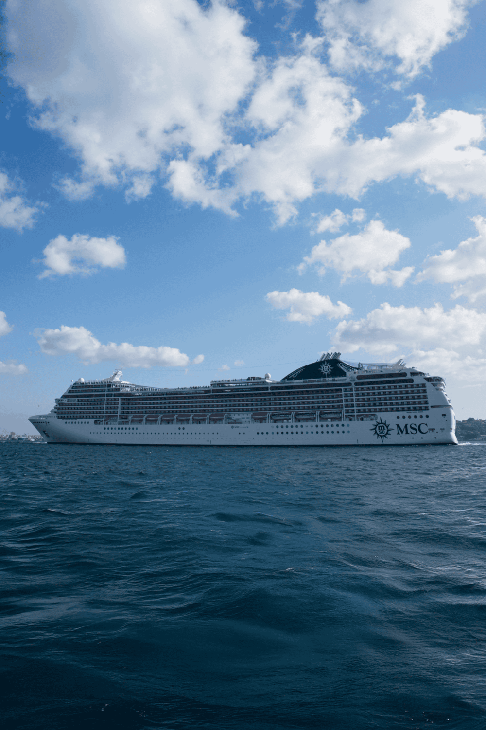 Luxurious cruise ship sailing on the ocean under a blue sky with clouds, representing vacation and travel planning.