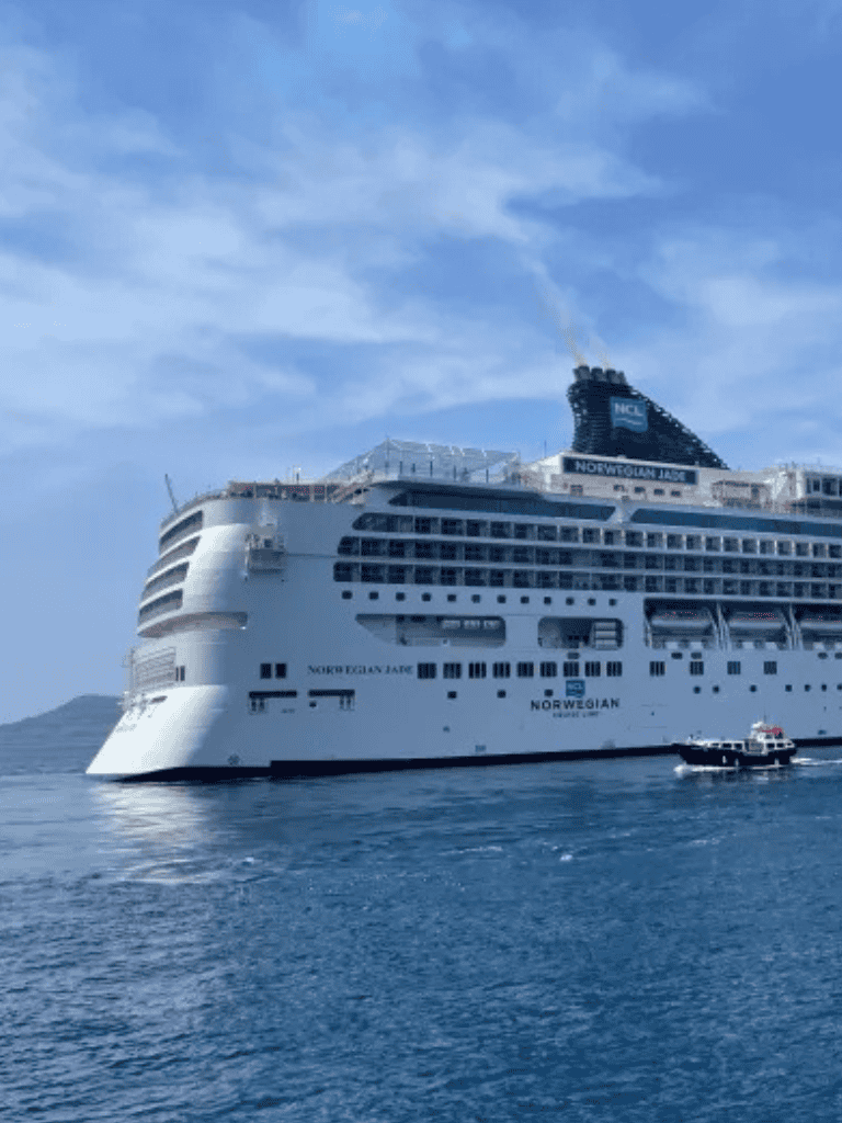 Luxurious cruise ship Norwegian Jade sailing in calm blue waters with clear sky background.