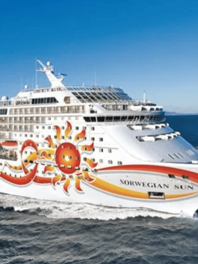 Luxury cruise ship Norwegian Sun with sun-themed artwork, sailing on clear blue ocean waters.