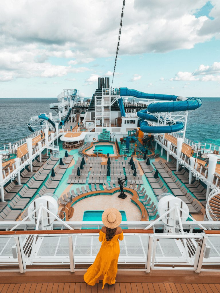 Relaxing on a cruise ship deck with water slides and pool, ocean view, sunny weather.