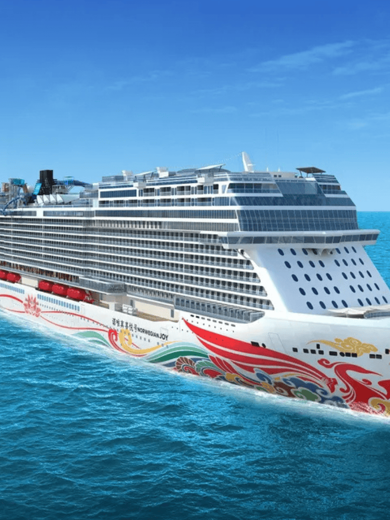 Luxurious cruise ship sailing on vibrant blue ocean, showcasing modern design and scenic views.