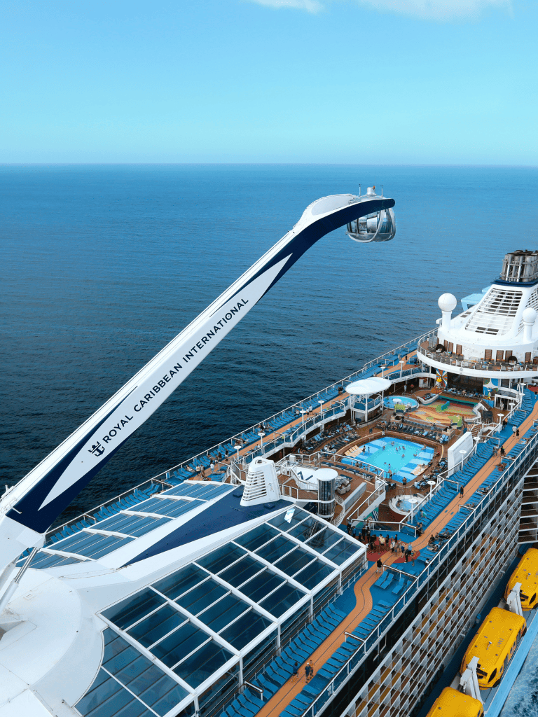 Luxury cruise ship featuring a vibrant outdoor pool and scenic ocean views, perfect for unforgettable vacation experiences. | Explore premium cruise vacations with Royal Caribbean International, including luxurious amenities and stunning sea vistas. | A Royal Caribbean cruise ship deck showcasing a pool, sunbathing areas, and panoramic ocean views, ideal for relaxation and adventure at sea.