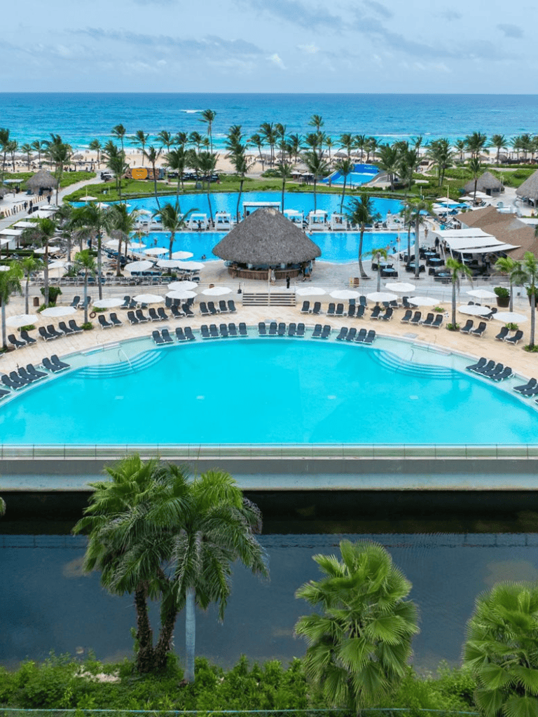 Poolside resort in tropical paradise with ocean view and lush palm trees.