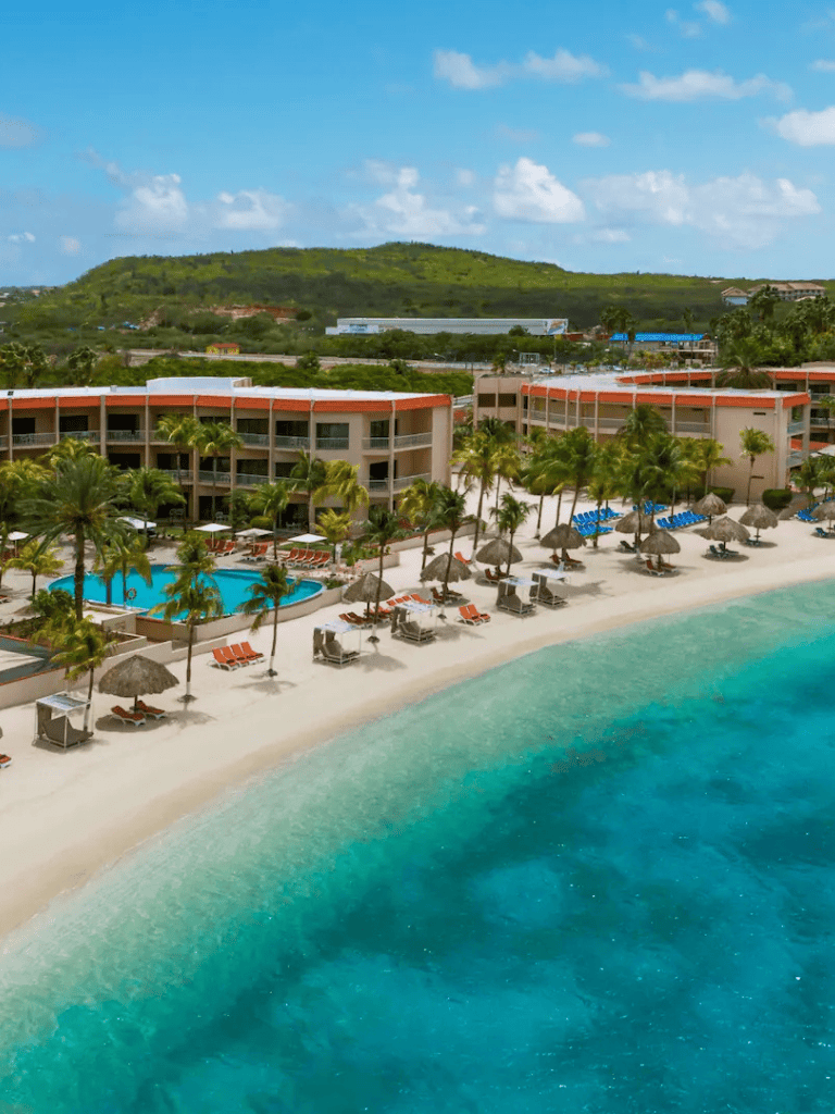 Beach resort with pool and palm trees in a tropical location.