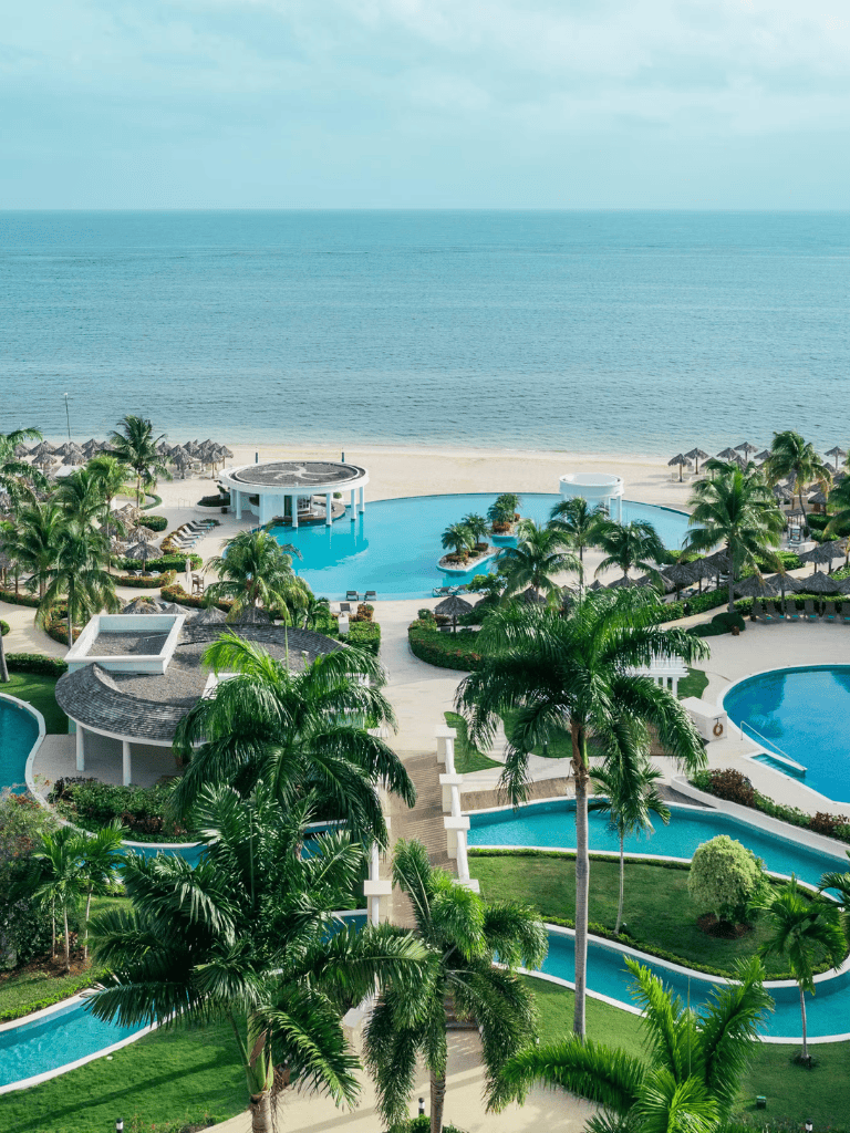 Luxurious beach resort with infinity pools and tropical palms overlooking the ocean.