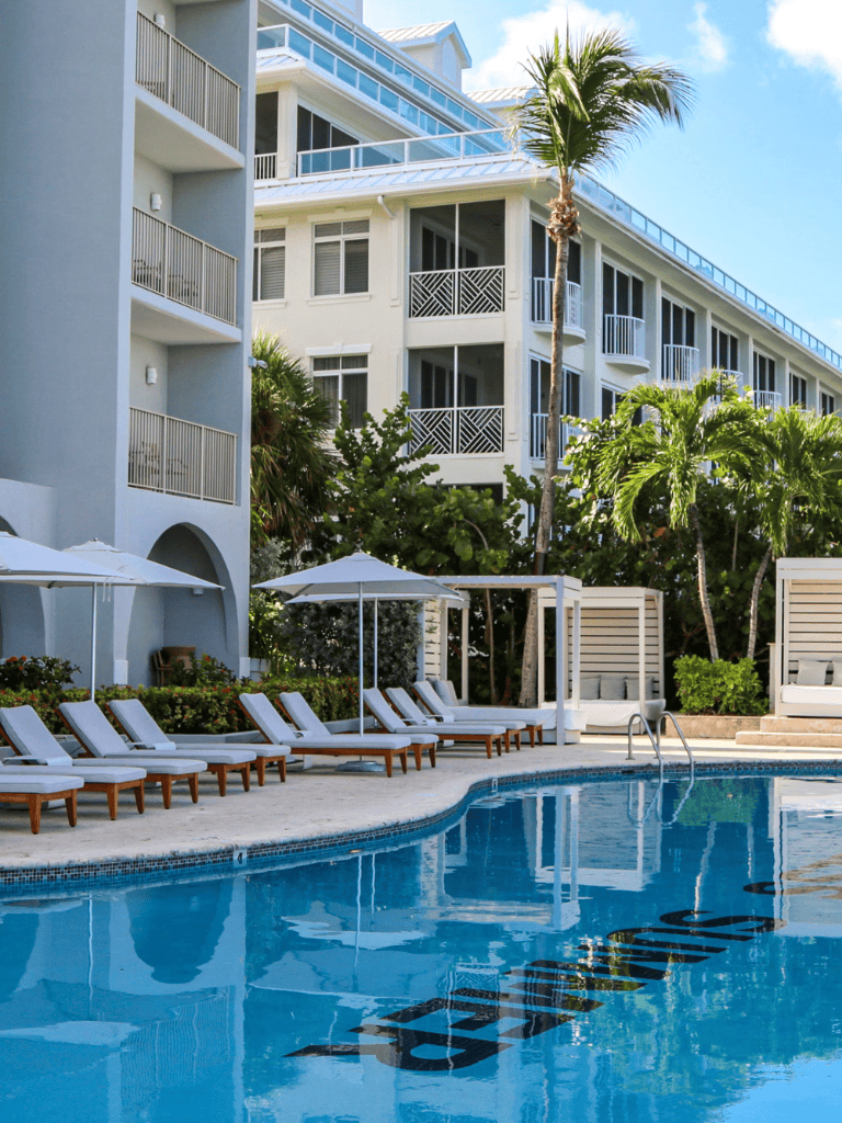 Relaxing resort pool with modern hotel building and palm trees, perfect for vacation in Miami Beach.