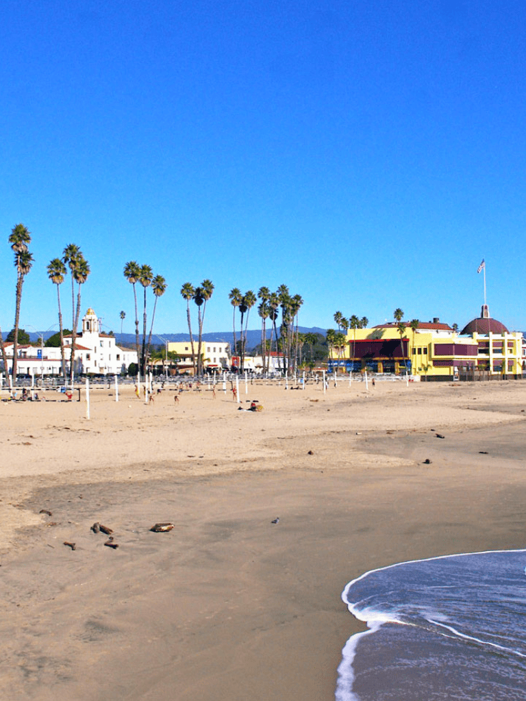 Quiet beach with palm trees and colorful buildings, scenic California coastal destination.