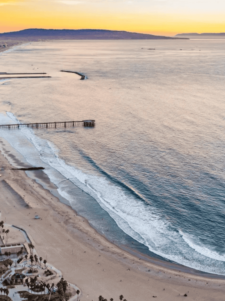 Sunset over Pacific Ocean at La Jolla Shores, California, coastal beach with calm waves.