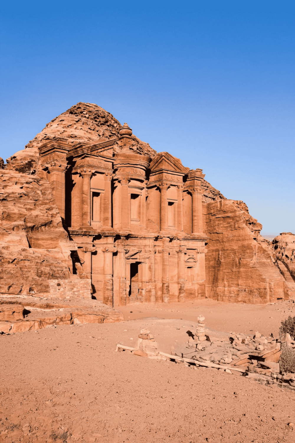 Ancient rock-cut architecture of Al-Khazneh in Petra, Jordan, under clear blue sky, archaeological wonder.